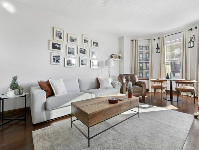 a living room with furniture a large window and dining table