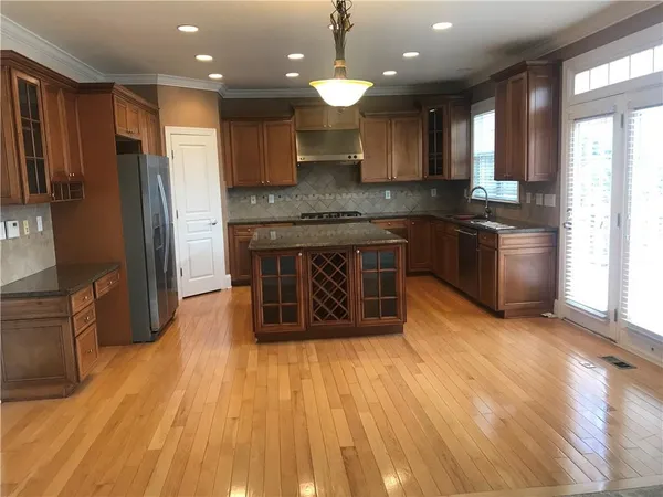 a kitchen with kitchen island granite countertop wooden floors stainless steel appliances a sink and a counter space