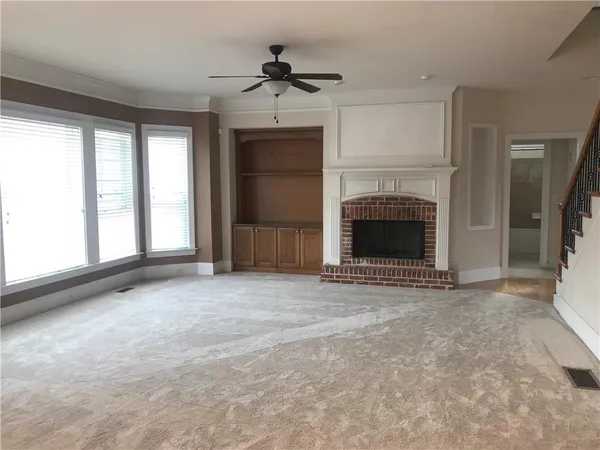 an empty room with windows and fireplace