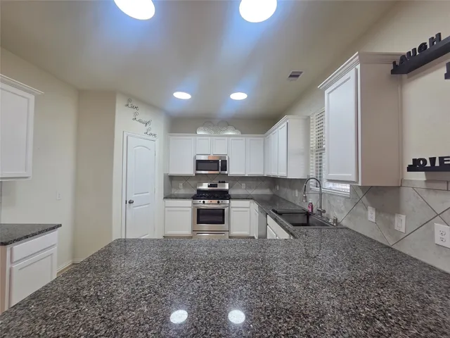 a kitchen with stainless steel appliances granite countertop a sink stove and refrigerator