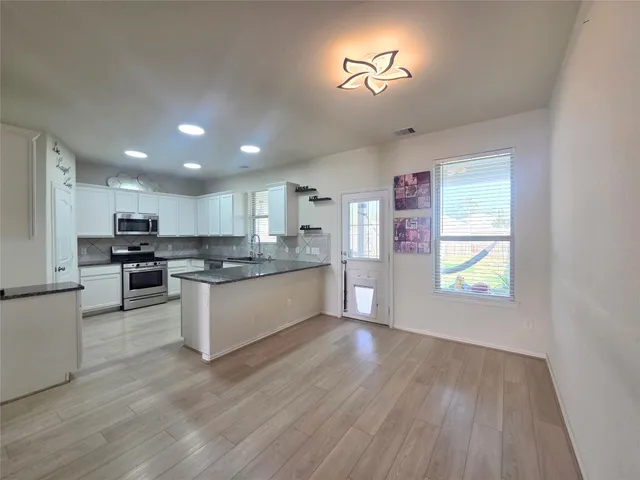 a large kitchen with stainless steel appliances granite countertop a stove a sink dishwasher and a oven with white cabinets