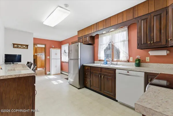 a kitchen with stainless steel appliances a refrigerator a stove a sink dishwasher and a dining table with wooden floor