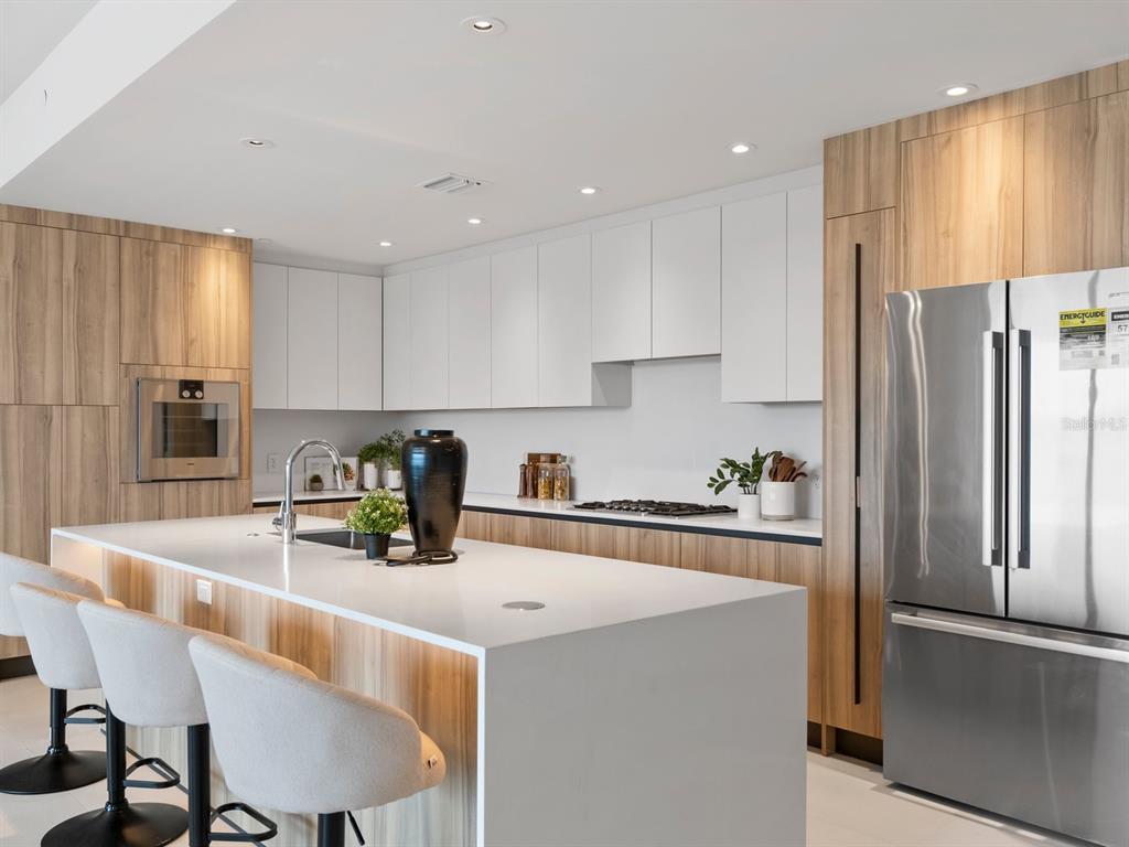 1020 Sunset Point Road, Unit 410 Clearwater, FL 33755 - Photo 4 of 27 a kitchen with refrigerator and chairs