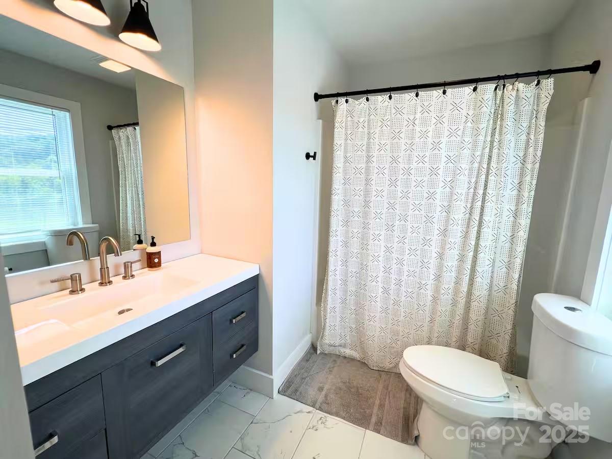 1057 Riverside Drive Asheville, NC 28804 - Photo 28 of 42 a bathroom with a sink a toilet and shower curtain