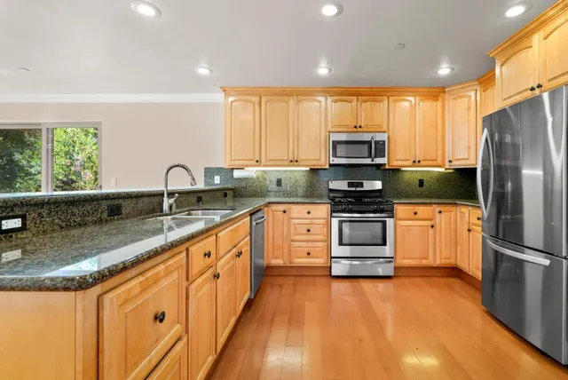 a kitchen with granite countertop a refrigerator and a stove top oven