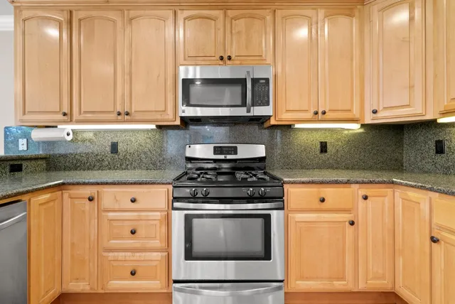 a kitchen with granite countertop white cabinets and stainless steel appliances