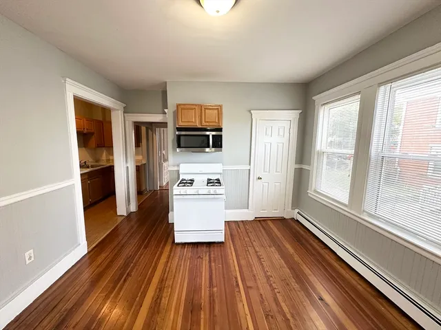 a kitchen with white cabinets and wooden floor