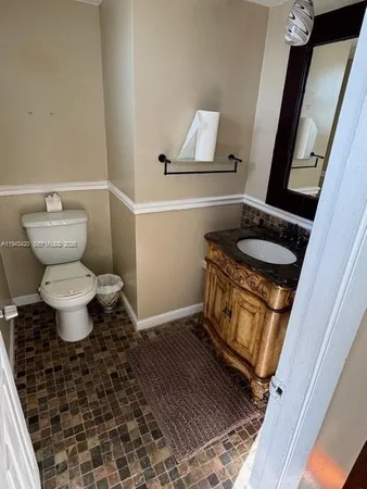 a bathroom with a granite countertop toilet and a sink