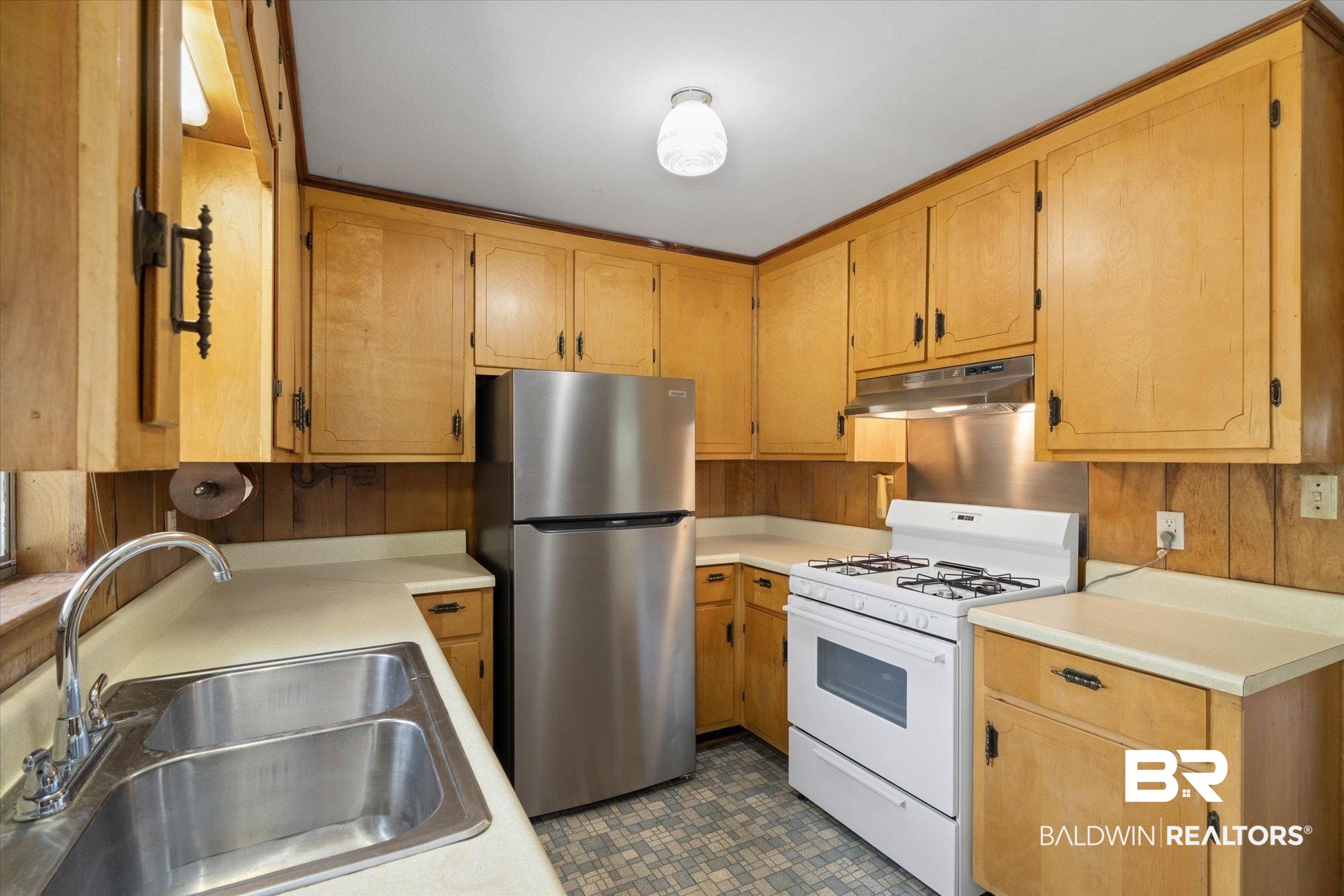 423 First Avenue Saraland, AL 36571 - Photo 8 of 20 Kitchen with white gas range, freestanding refrigerator, under cabinet range hood, a sink, and light countertops