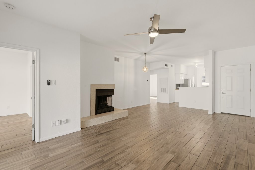 2450 Wickersham Lane, Unit 1006 Austin, TX 78741 - Photo 2 of 27 an empty room with wooden floor ceiling fan and kitchen view