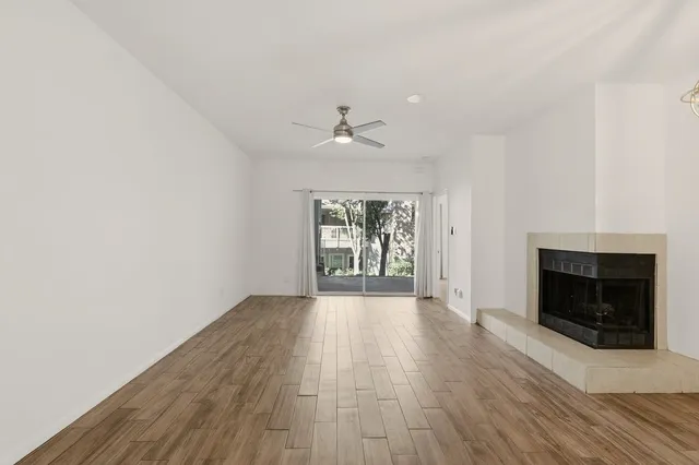 an empty room with wooden floor fireplace and windows
