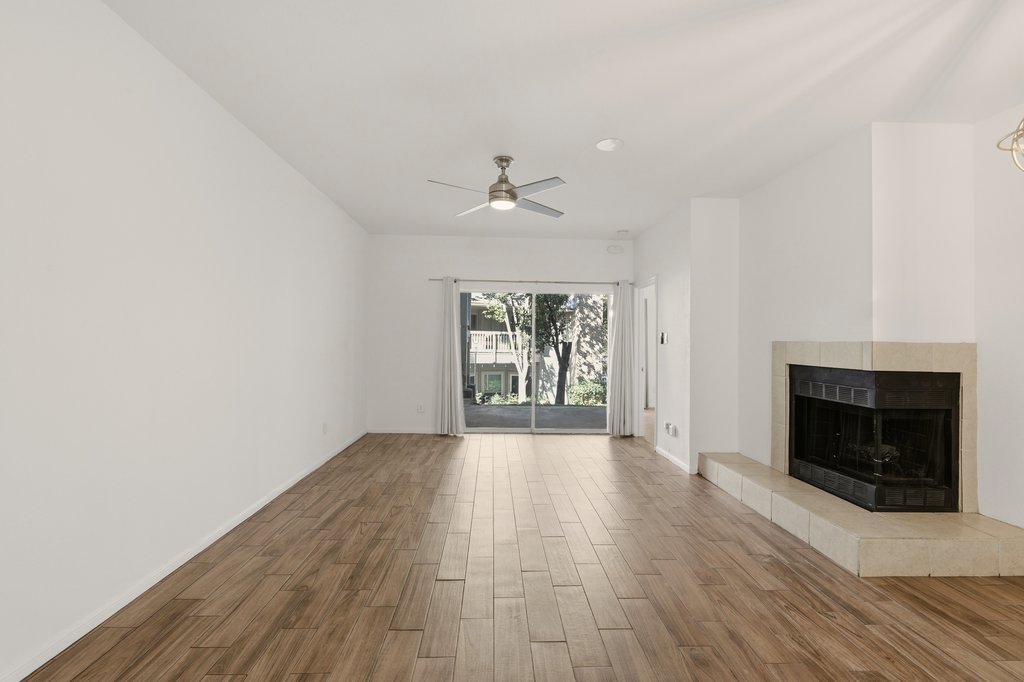 2450 Wickersham Lane, Unit 1006 Austin, TX 78741 - Photo 4 of 27 an empty room with wooden floor fireplace and windows