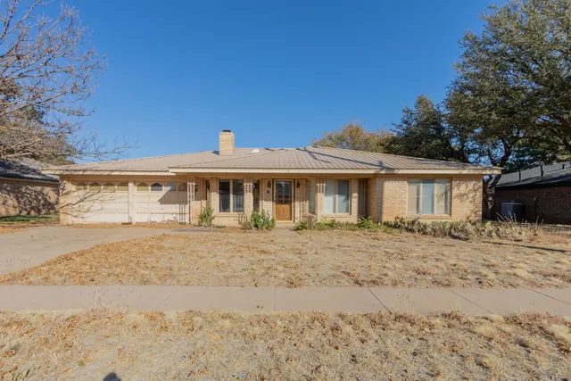 a front view of a house with a dirt yard and a large tree