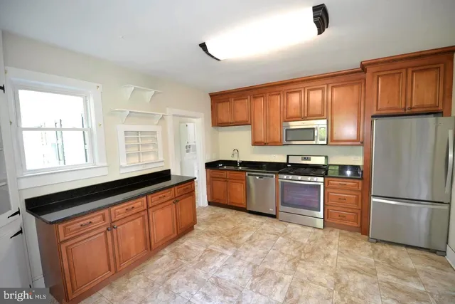a kitchen with granite countertop stainless steel appliances a refrigerator stove top oven and sink
