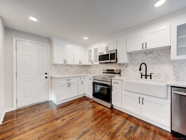 a kitchen with granite countertop a sink cabinets and stainless steel appliances
