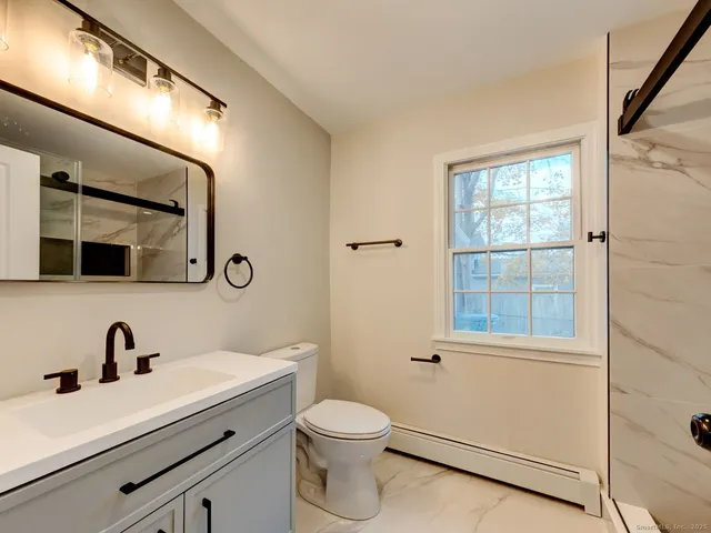 a bathroom with a toilet a sink a mirror a vanity and window