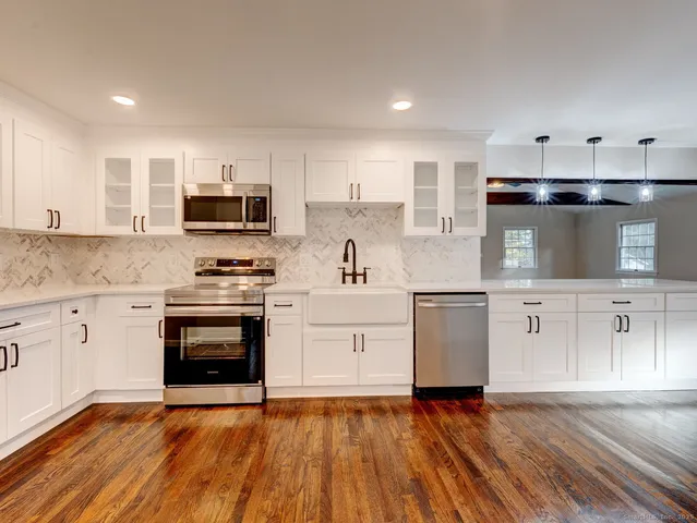 a kitchen with stainless steel appliances a stove top oven a sink and cabinets