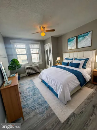 a spacious bedroom with a bed a couch and a potted plant on the dresser