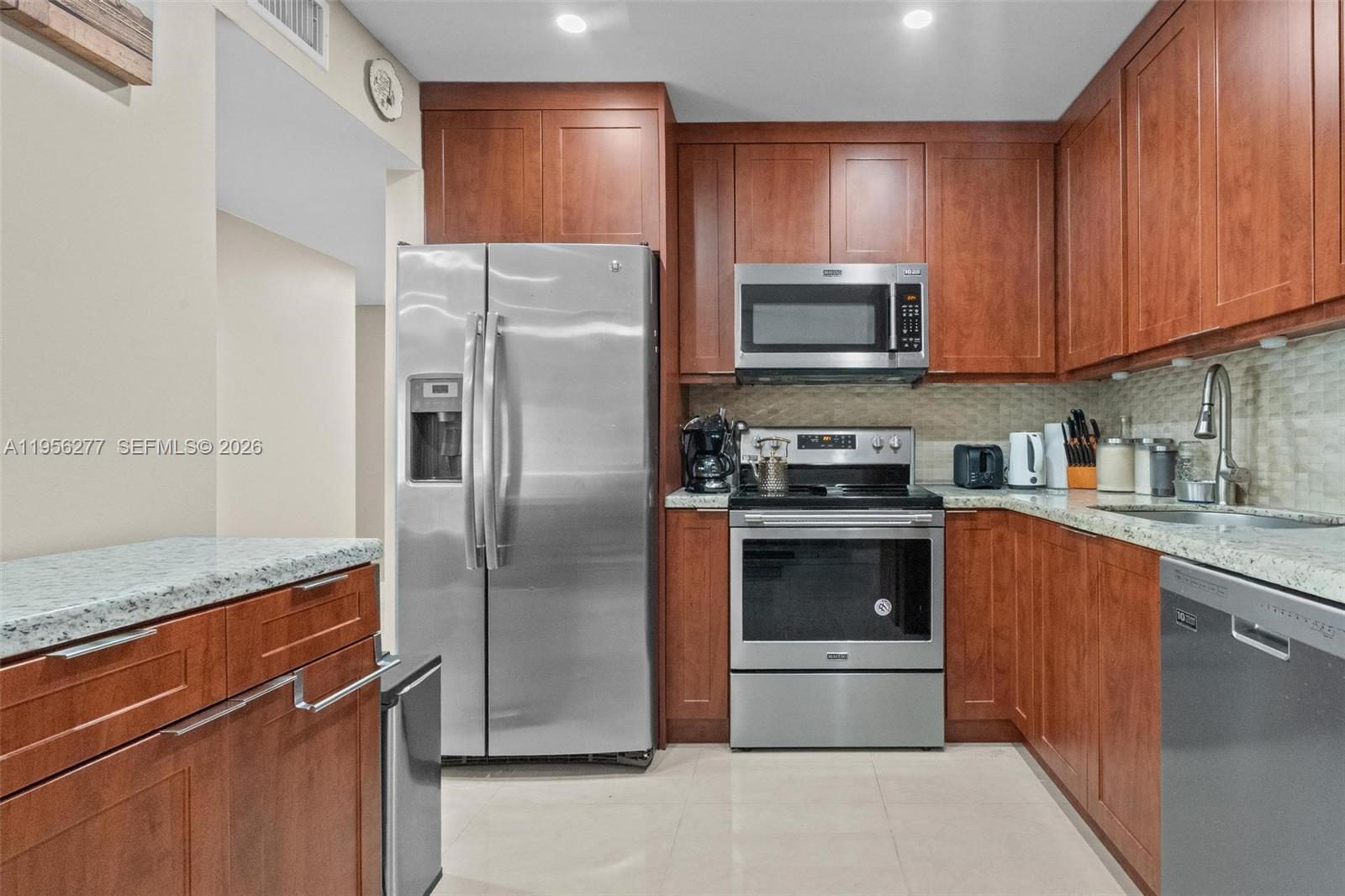 a kitchen with granite countertop a refrigerator and a stove top oven