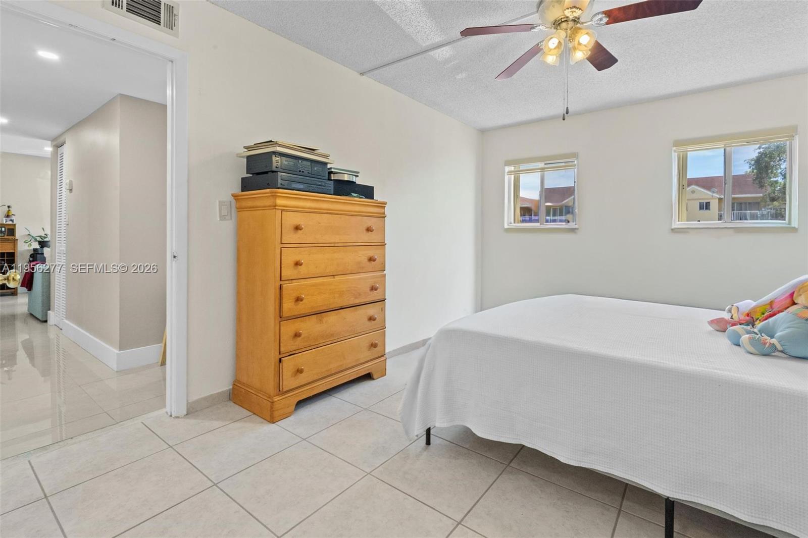 13810 Southwest 112th Street, Unit 102 Miami, FL 33186 - Photo 18 of 28 a bedroom with a bed and a chandelier