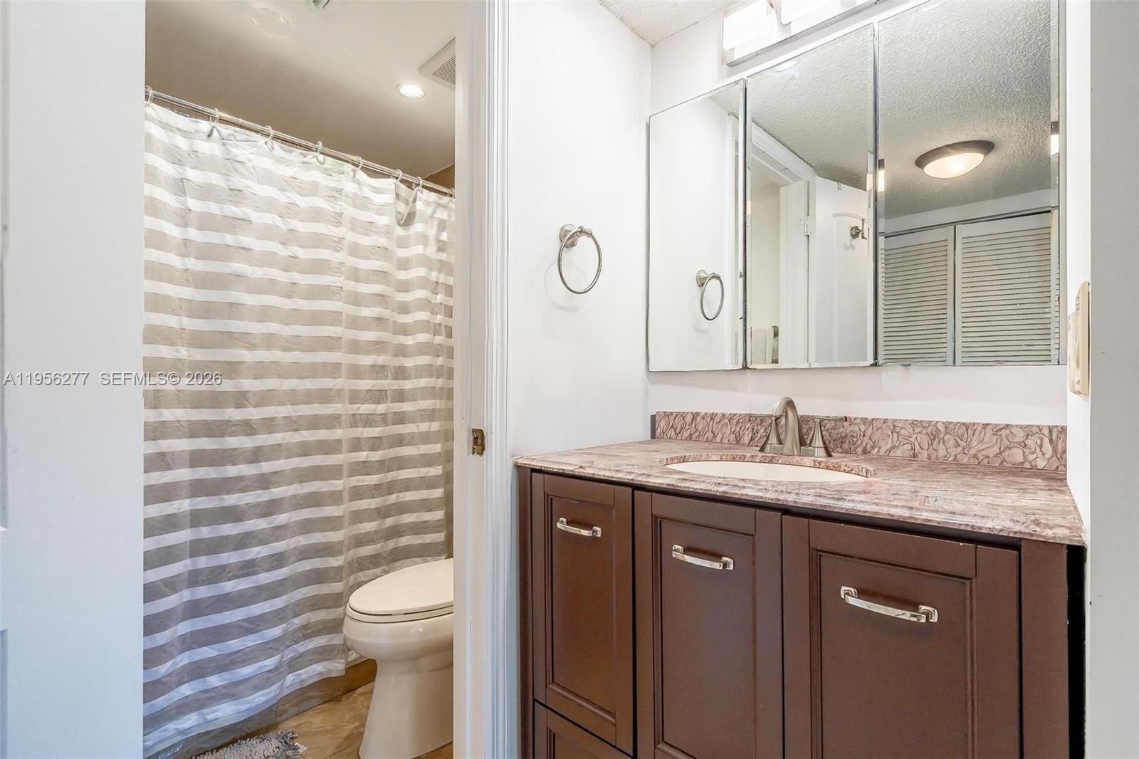 13810 Southwest 112th Street, Unit 102 Miami, FL 33186 - Photo 20 of 28 a bathroom with a granite countertop toilet sink and mirror