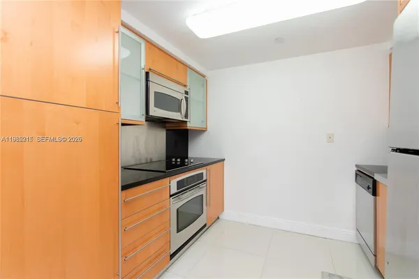 a kitchen with stainless steel appliances granite countertop a refrigerator a stove and a sink with wooden floor