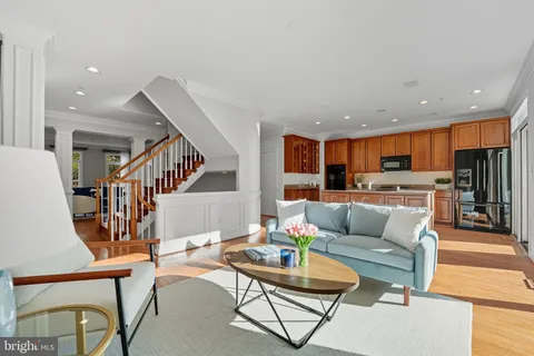 a living room with furniture kitchen view and a wooden floor