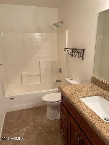 a bathroom with a granite countertop sink a toilet and shower