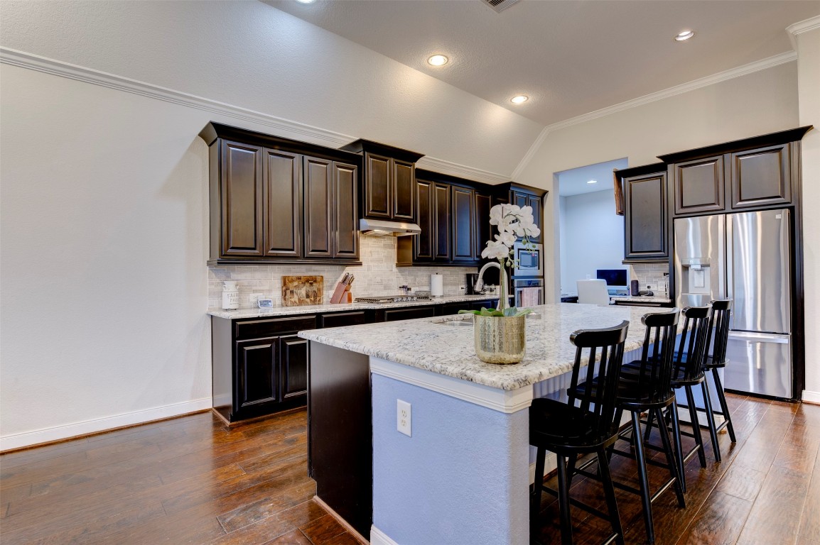 6242 Avon Landing Lane Spring, TX 77379 - Photo 16 of 42 a kitchen with kitchen island granite countertop a stove top oven a sink dishwasher a dining table and chairs with wooden floor