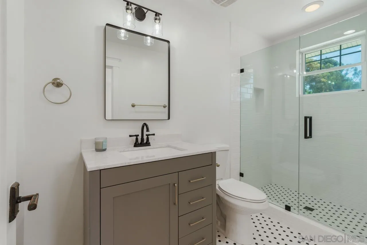 11823 Rocoso Road Lakeside, CA 92040 - Photo 26 of 48 a bathroom with a toilet a sink a glass door a shower and a mirror