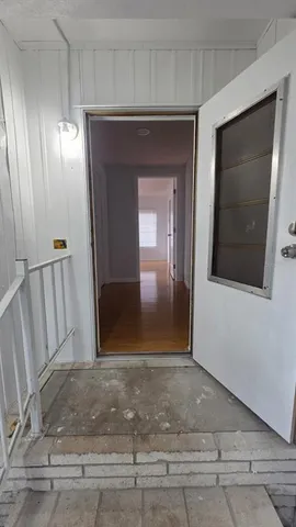a view of a hallway with wooden floor and staircase