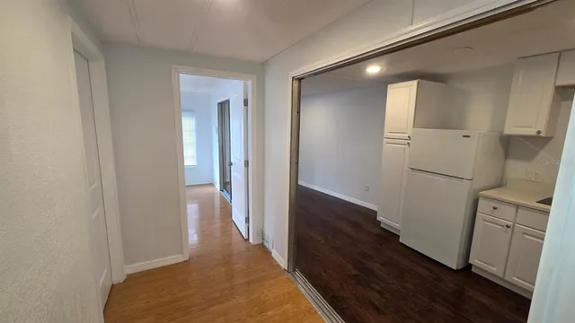a view of a hallway with wooden floor and cabinets
