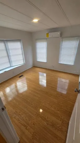 a view of empty room with window and wooden floor