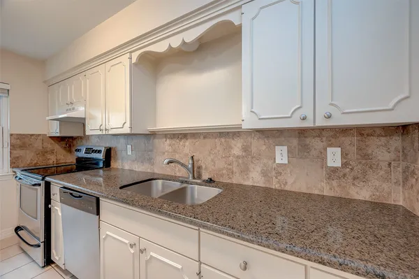 a kitchen with stainless steel appliances granite countertop a sink a stove and white cabinets