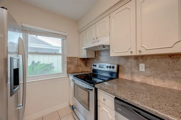 a kitchen with stainless steel appliances granite countertop a sink a stove and a refrigerator