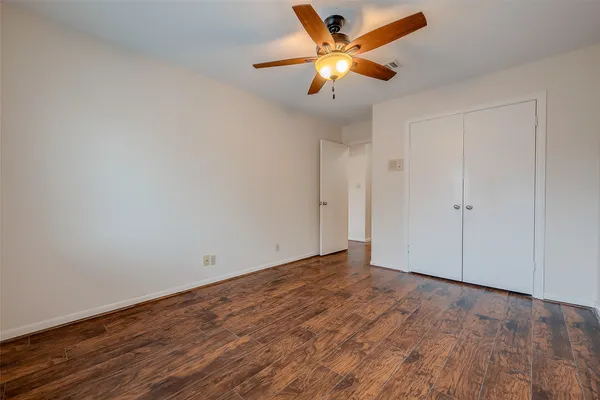 an empty room with wooden floor and a ceiling fan