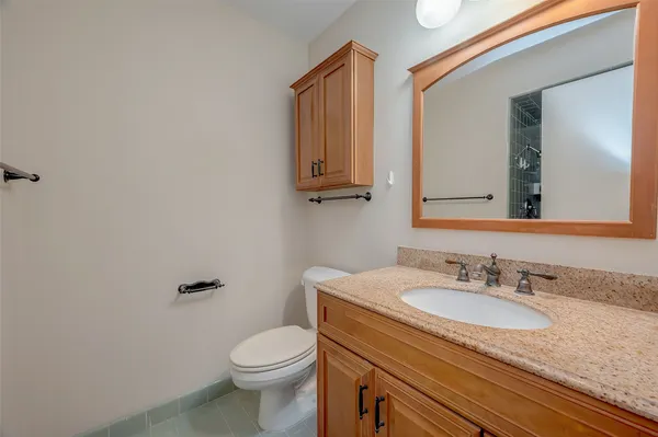 a bathroom with a granite countertop toilet sink and mirror