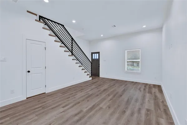 a view of an empty room with wooden floor and stairs