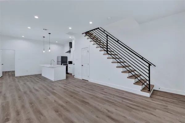 a view of an empty room with wooden floor and stairs