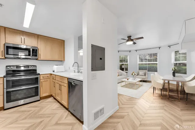 a kitchen with stainless steel appliances granite countertop a stove top oven a sink dishwasher and white cabinets with wooden floor