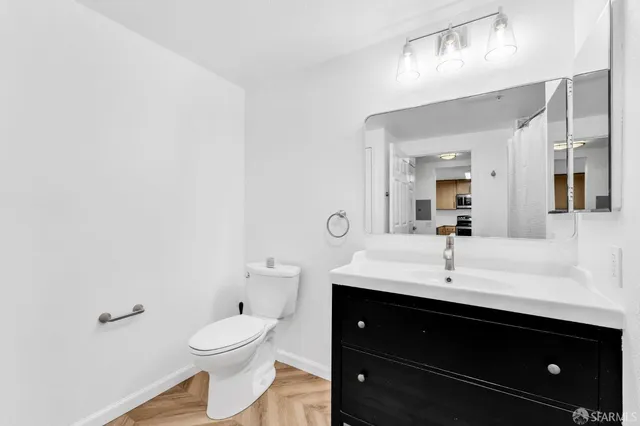 a bathroom with a toilet a sink a mirror and vanity