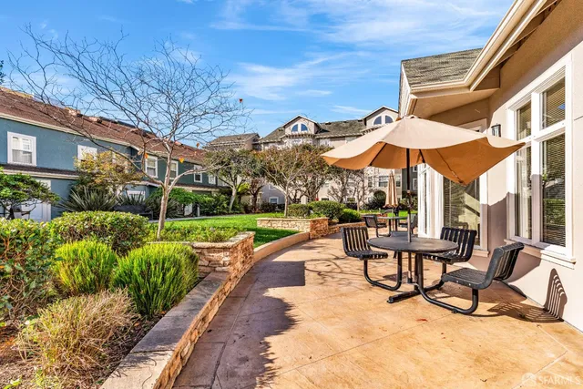 a view of a patio with a table and chairs under an umbrella