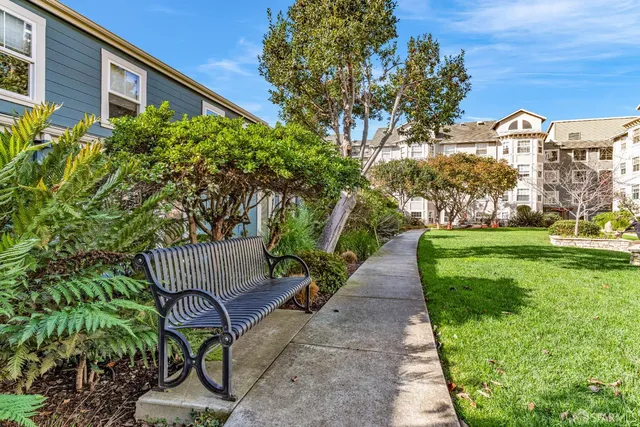 a kitchen with stainless steel appliances granite countertop a stove top oven a sink dishwasher and white cabinets with wooden floor