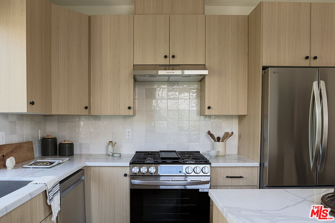 5117 Coringa Drive Los Angeles, CA 90042 - Photo 11 of 27 a kitchen with stainless steel appliances granite countertop a stove a refrigerator and a white cabinets