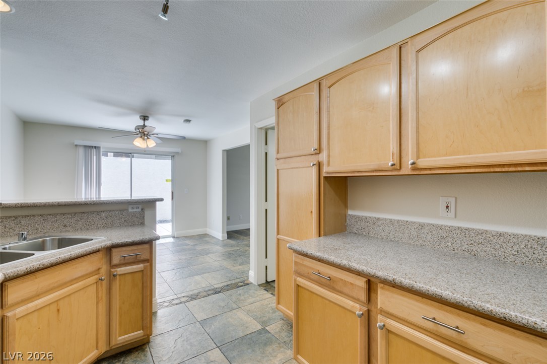 200 Luninborg Street Henderson, NV 89074 - Photo 20 of 40 Ample counter space and light wood cabinetry define this kitchen, seamlessly flowing into the dining area with a sliding glass door.