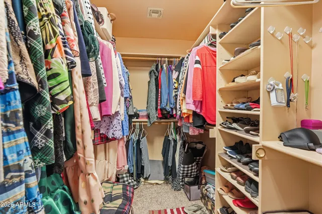 a view of walk in closet with clothes and shoes