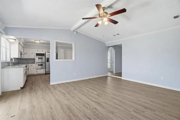 a view of an empty room with window and wooden floor
