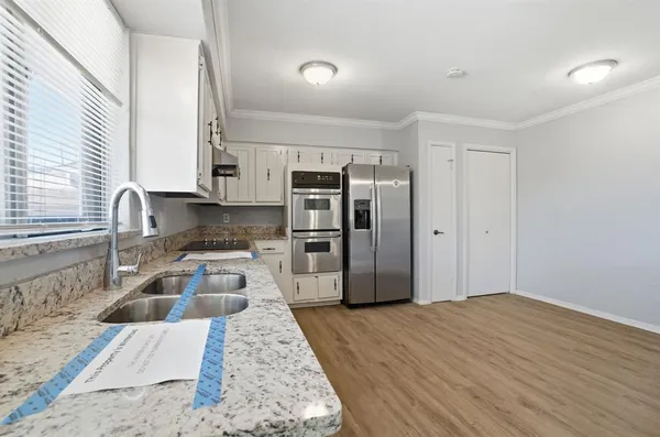 a kitchen with granite countertop a refrigerator sink and wooden cabinets