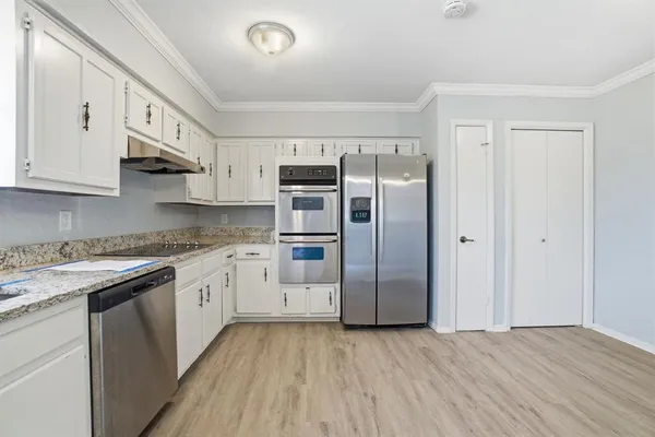 a kitchen with stainless steel appliances granite countertop a refrigerator sink and white cabinets