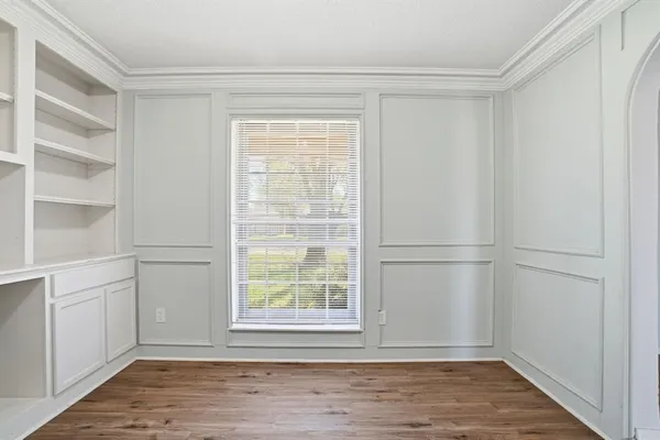 a view of an empty room with wooden floor and a window